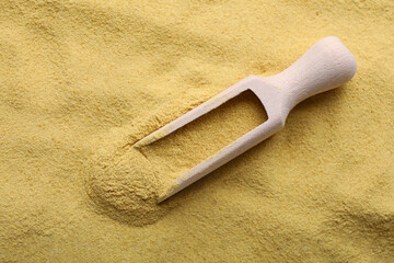 Wooden spoon of granulated brewer`s yeast on powder, top view