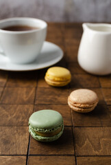 Colorful french macarons or macaroons (almond cookies) with a cup of tea on the  dark background