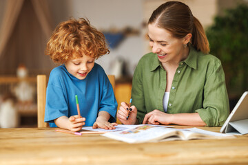 Fototapeta Cheerful mother doing homework with son at home obraz