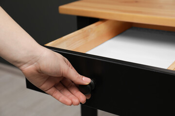 Woman opening empty desk drawer indoors, closeup view