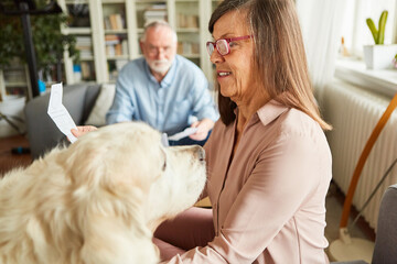 Seniorin mit Hund sortiert mit ihrem Mann Kassenzettel