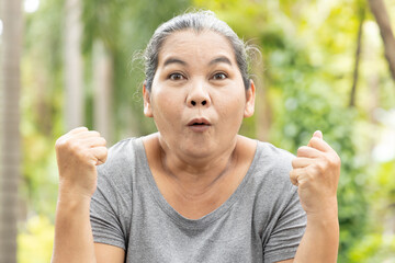 Exciting old asian senior woman feeling happy and positive in outdoor green park