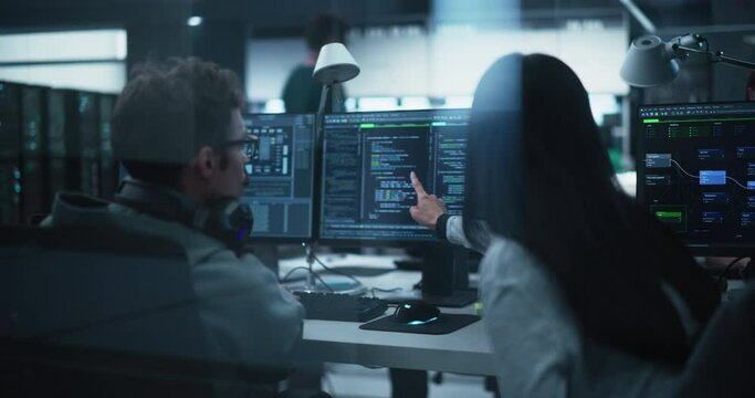 Young Team of Specialists Working on Desktop Computers and Having a Conversation at a Workplace. Female and Male Software Developers Discussing a Solution for Their Artificial Intelligence Project