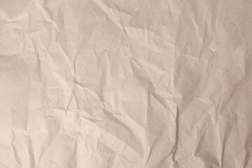 Sheet of crumpled light brown paper as background, top view