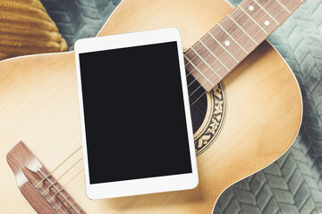 Acoustic guitar and digital tablet on couch