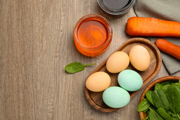 Painted Easter eggs with natural organic dyes (spinach and carrot) on wooden table, flat lay. Space for text