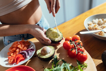 Fintess woman making a healthy poke bowl in the kitchen at home.