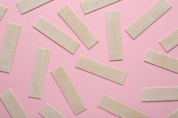 Many sticks of tasty chewing gum on pink background, flat lay