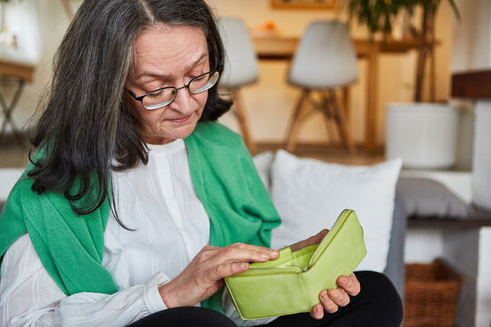 Seniorin schaut besorgt in ihre leere Geldbörse