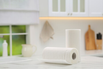 Rolls of paper towels on white marble table in kitchen. Space for text