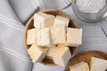 Tasty marshmallows with powder sugar on white wooden table, flat lay