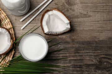 Delicious vegan milk and coconuts on wooden table, flat lay. Space for text