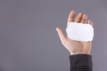 Man holding sheet of torn paper on grey background, closeup. Mockup for design