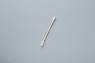 One wooden cotton bud on light grey background, top view