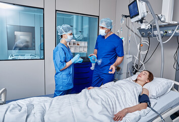 Female unconscious patient attached to medical monitoring equipment in intensive care unit with...