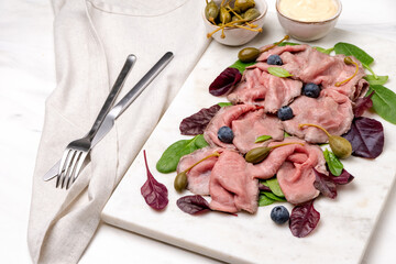 Roast beef with spinach leaves capers and blueberries. healthy lunch keto diet food