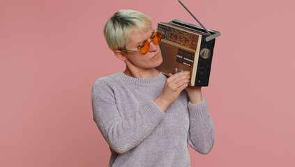 Millennial woman with short hair using retro tape record player to listen music, disco dancing of...