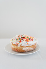 closeup of donut with sprinkles and white icing with a white backdrop 
