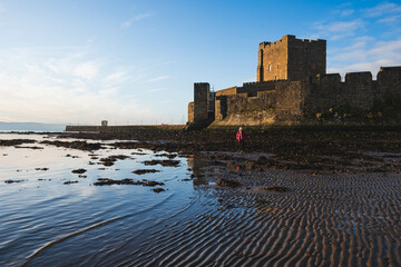 Silhouette of Carrickfergus Castle Beach, Northern Ireland, wide angle lens with sunrise, blue sky,...