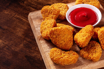 Chicken nuggets with ketchup on a rustic wooden background, with copy space. A crispy meat snack at a restaurant, a fast food dish on a table