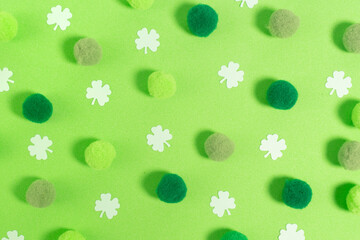 Saint Patrick´s green background with green cotton spots and little paper clovers. Top view