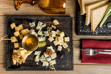 Fototapeta na wymiar Cheese plate with grapes and nuts on wooden table, top view