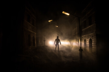 Sad man alone walking along the alley in night foggy park. Decorative ruined city.
