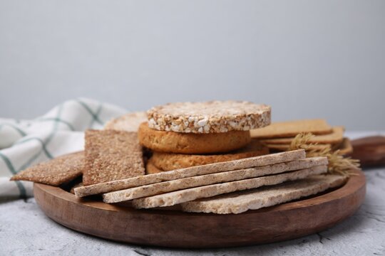 Rye crispbreads, rice cakes and rusks on white textured table, space for text