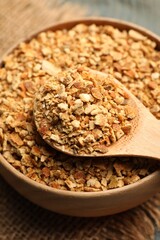 Bowl and spoon with dried orange zest seasoning on table, closeup