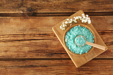 Plakat Turquoise sea salt and beautiful flowers on wooden table, top view. Space for text