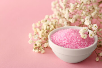 Aromatic sea salt and beautiful flowers on pink background, closeup. Space for text