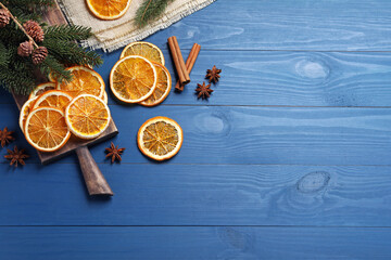 Dry orange slices, anise stars and fir tree branches on blue wooden table, flat lay. Space for text