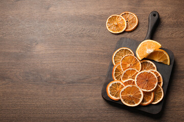 Obraz na płótnie Canvas Dry and fresh orange slices on wooden table, flat lay. Space for text