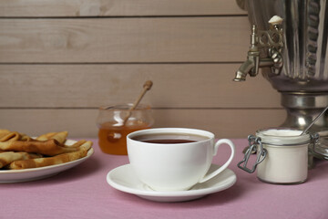 Vintage samovar, cup of hot drink and snacks served on table. Traditional Russian tea ceremony