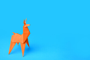 Origami art. Handmade orange paper deer on light blue background, space for text