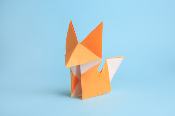 Origami art. Handmade orange paper fox on light blue background