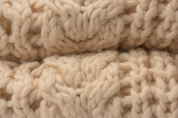 A fragment of beige knitted fabric, knitted from white sheep wool.