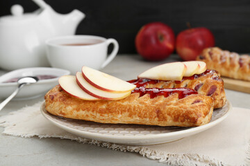 Fresh tasty puff pastry with jam and apples on white textured table, closeup