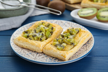 Fresh tasty puff pastry with kiwi on blue wooden table, closeup