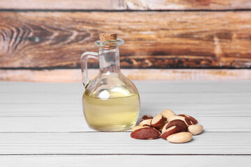 Obraz premium Tasty Brazil nuts and bottle with oil on white wooden table