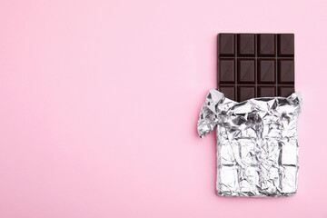 Tasty chocolate bar on pink background, top view. Space for text