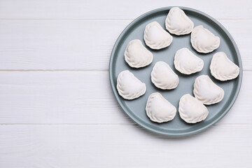 Fototapeta na wymiar Raw dumplings (varenyky) on white wooden table, top view. Space for text