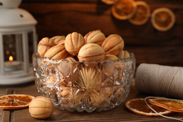 Bowl of delicious nut shaped cookies and dried orange slices on wooden table, closeup