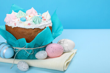 Traditional Easter cake with meringues and painted eggs on light blue background, space for text