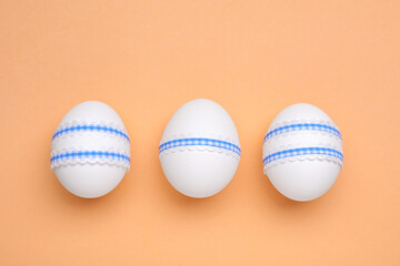 Beautifully decorated Easter eggs on pale orange background, flat lay