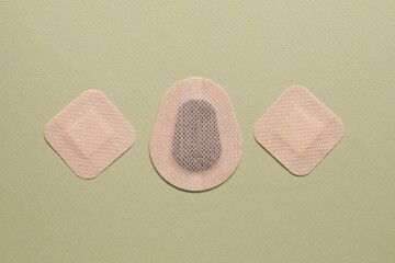 Different contraceptive patches on green background, flat lay