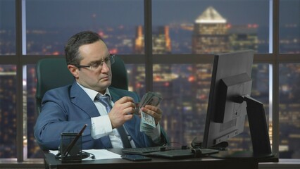 Businessman counting banknotes at the office at night