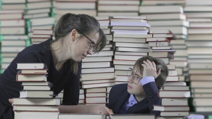 Mother teach boy with suit in a library, teacher and pupil