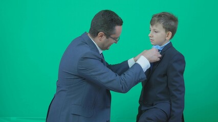 Father arrange son suit, man and child shaking hands, green screen - Powered by Adobe