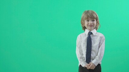 Portrait of innocent blonde hair little child with tie move hands, green screen, conceptual